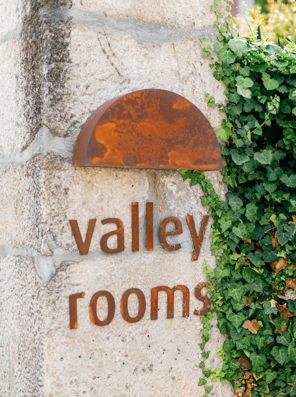 Rustic 'Valley Rooms' sign nestled against stone and ivy at Six Senses Douro Valley, Portugal.