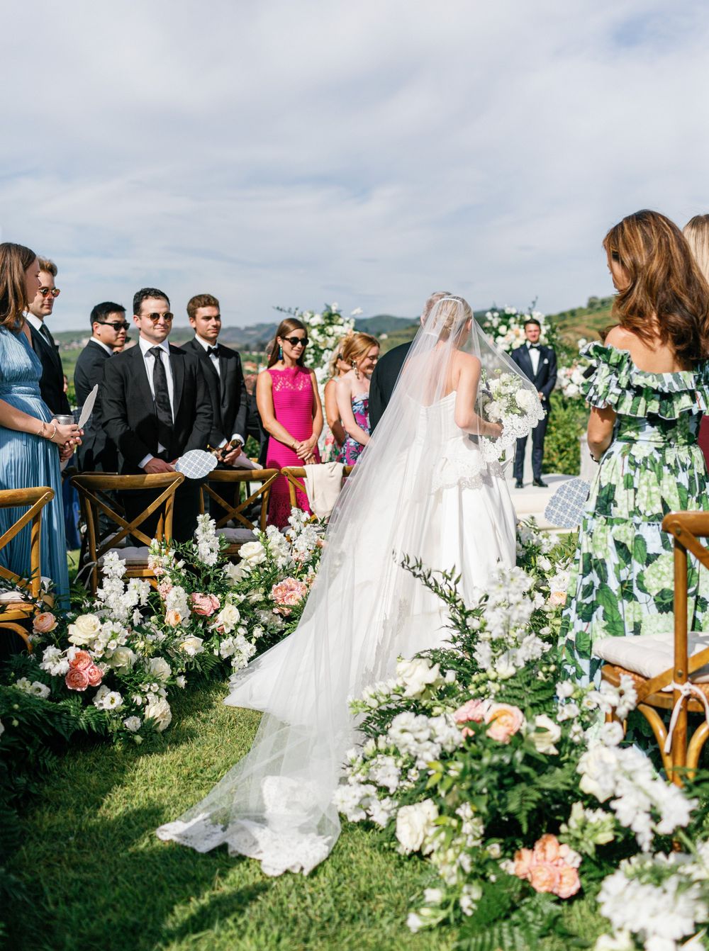 Bride walks down the aisle, surrounded by floral arrangements at Six Senses Douro Valley.