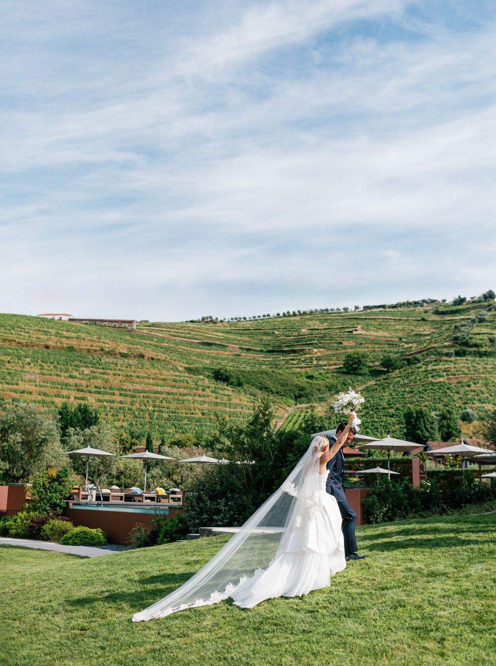 Bride and groom raise their hands in joy against the vineyard backdrop at Six Senses Douro Valley.