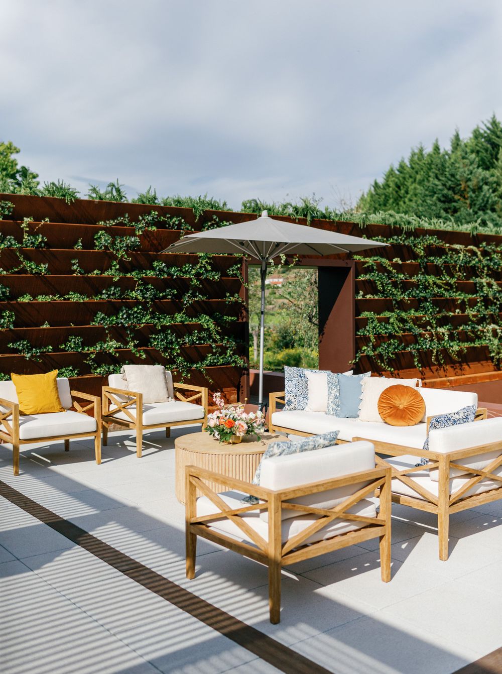 Comfortable, modern outdoor lounge furniture set up for cocktail hour, surrounded by lush greenery.