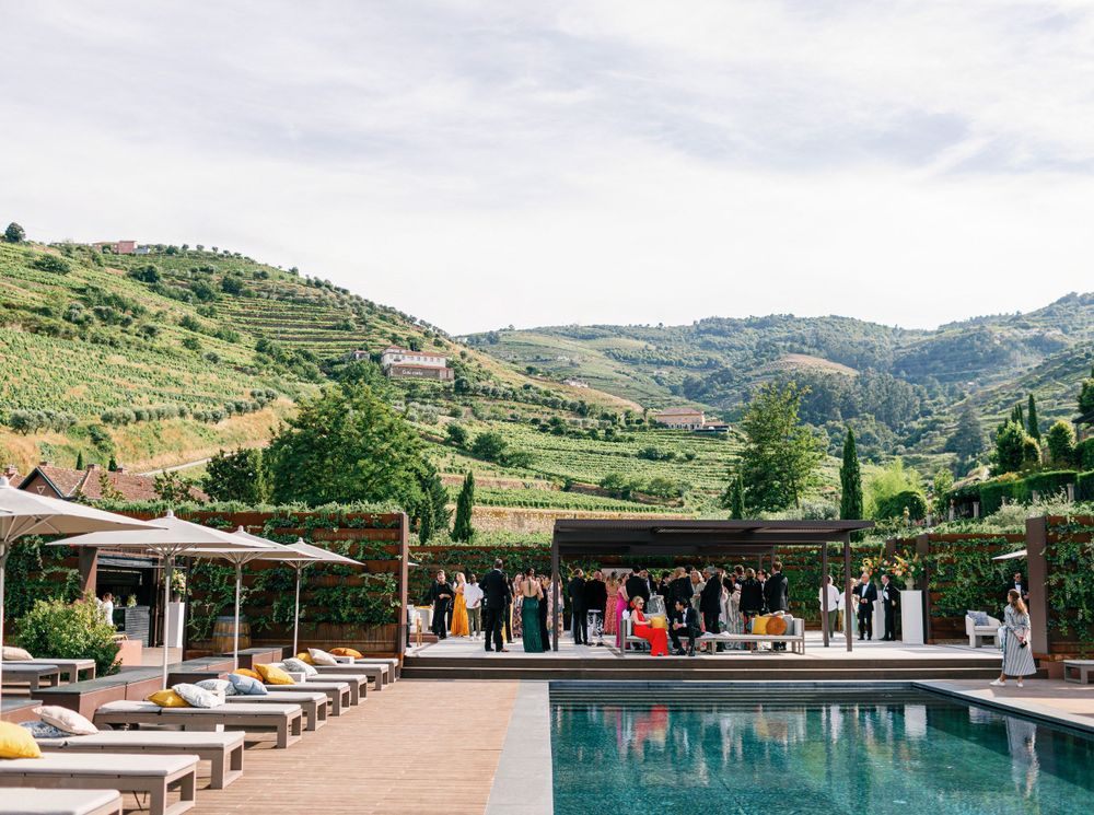 Guests mingling by the poolside with picturesque views of the Douro Valley vineyards in the background.