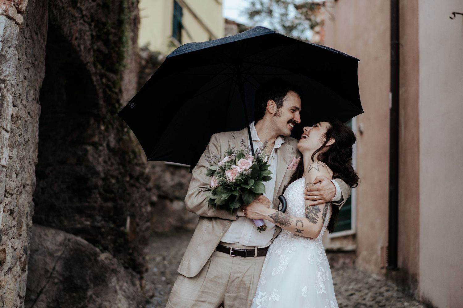 Servizio fotografico di coppia a Montemarcello La Spezia durante il loro matrimonio con l'ombrello mentre sorridono e sono felici