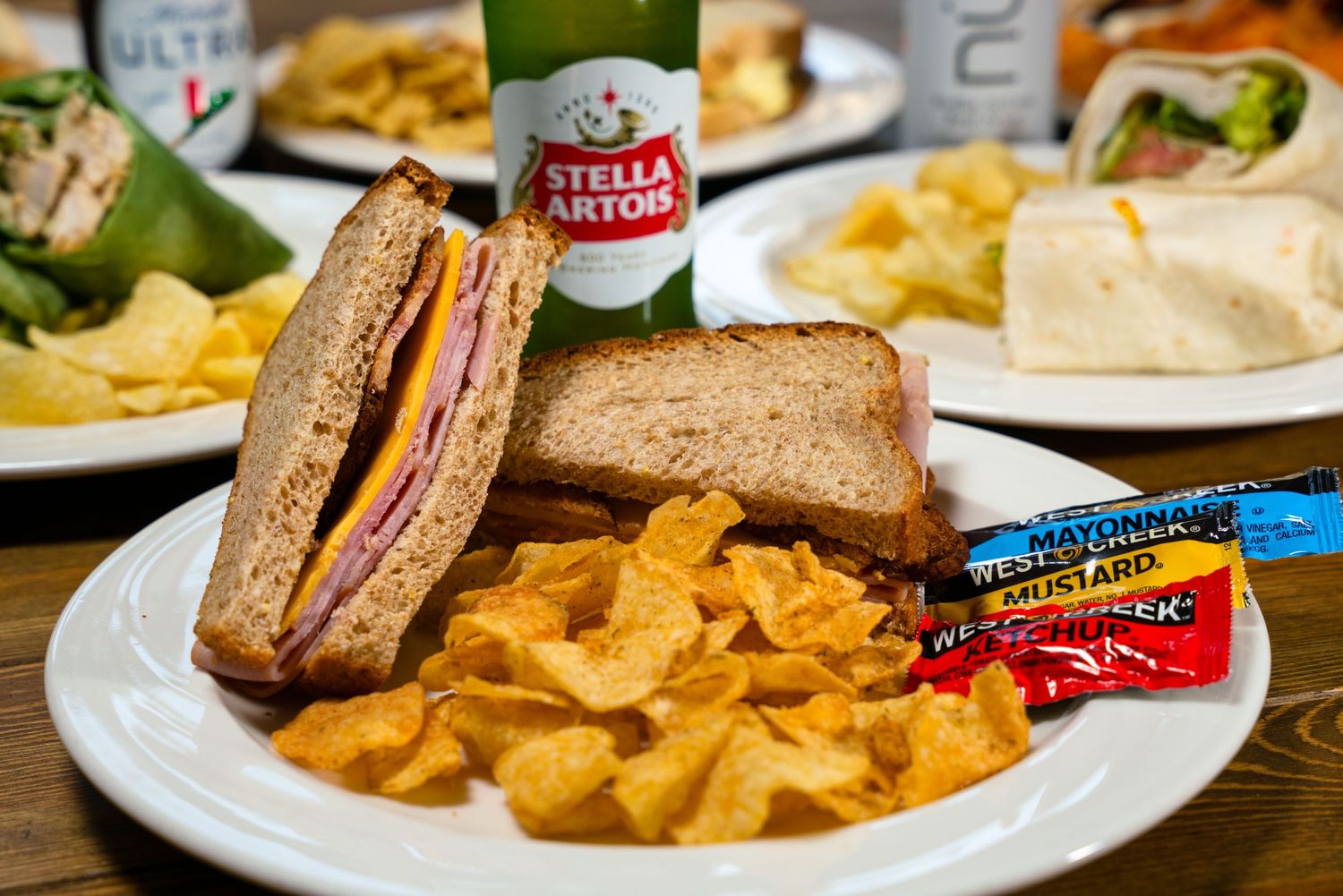 Classic sandwich with potato chips served on white plate with condiment packets.
