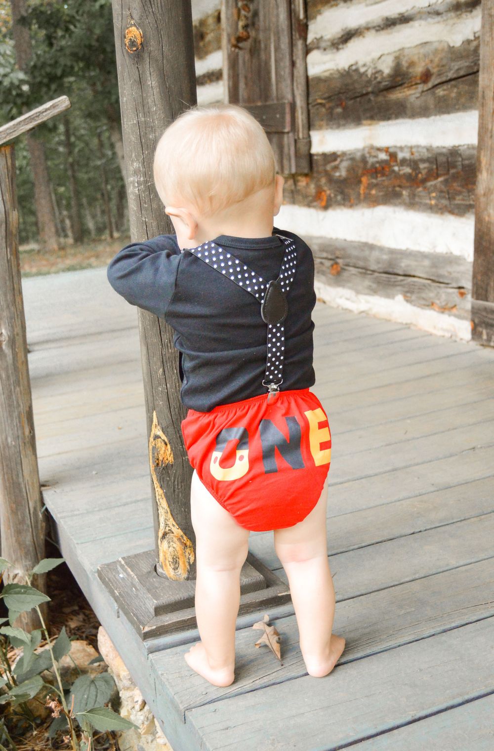 child wearing Mickey Mouse themed outfit for one year old photo session