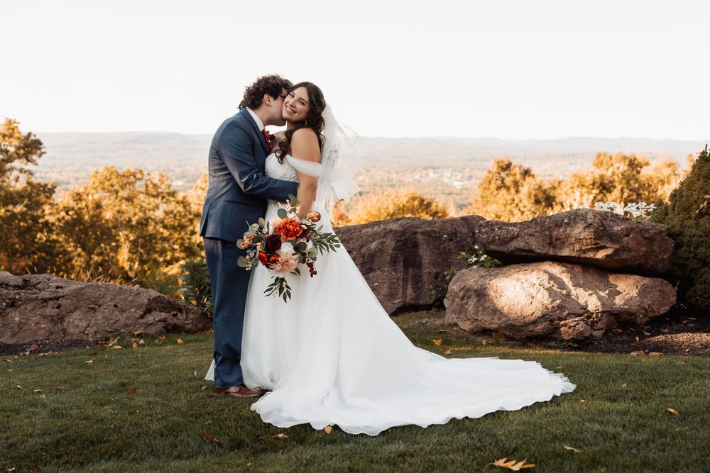 A romantic sunset wedding portrait captured on a mountain overlook with dramatic fall colors.