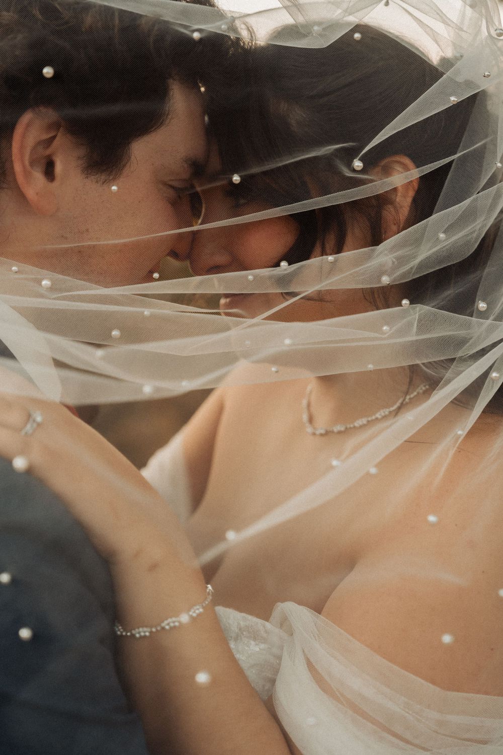 Romantic close-up through sheer veil with sparkling details and soft lighting.