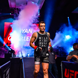 MMA fighter entering arena with dramatic colored smoke effects during pre-fight entrance.