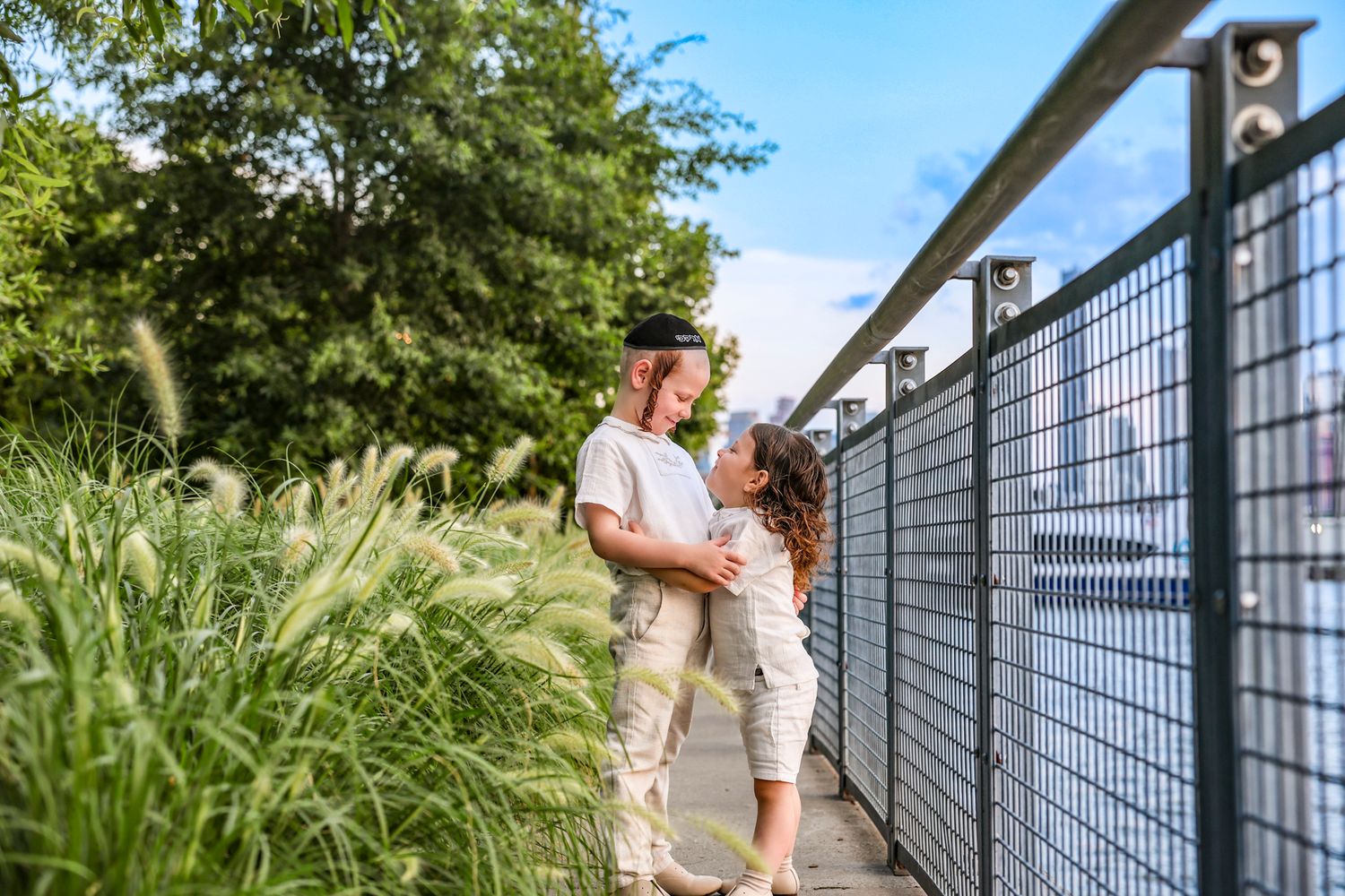 Young couple sharing a tender moment on a bridge walkway surrounded by lush greenery.