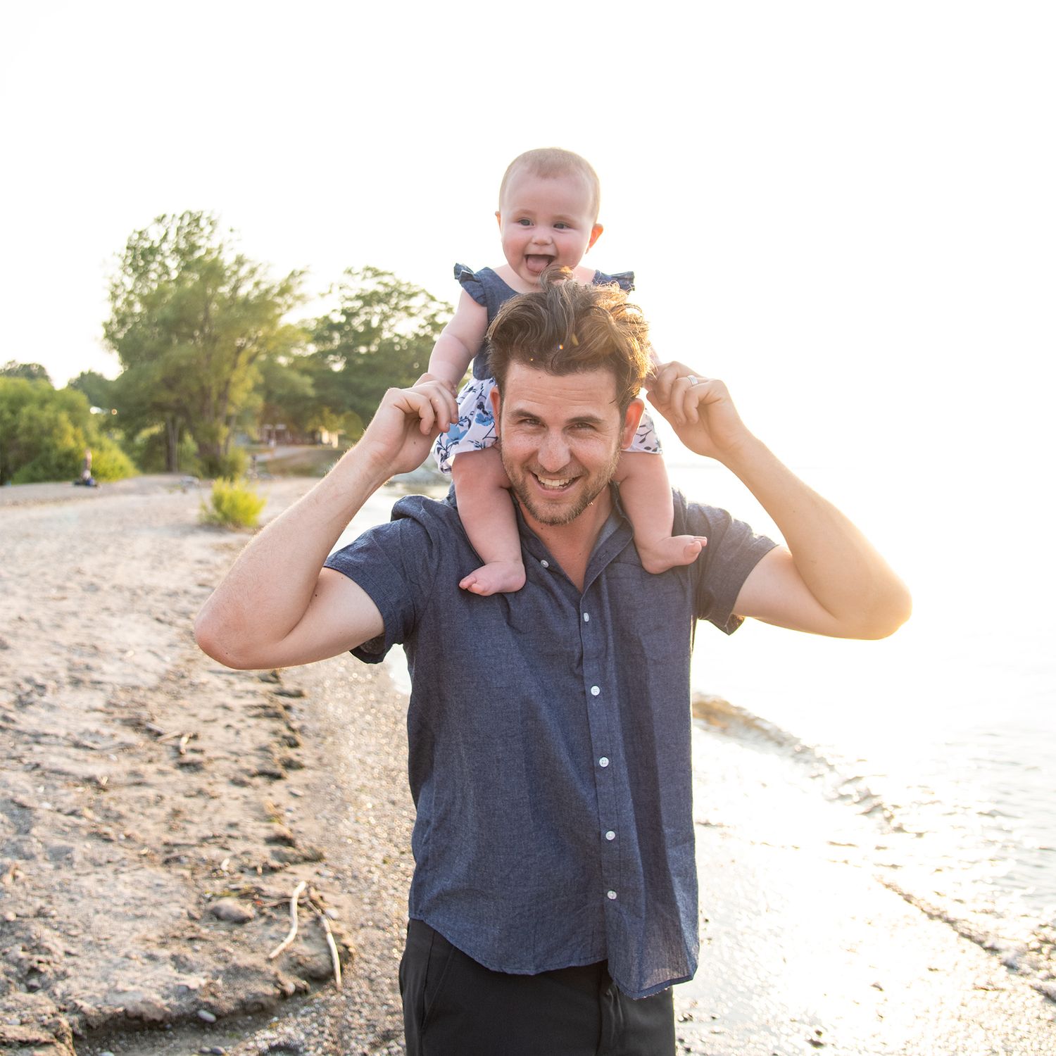 A joyful moment together at sunset on a rocky beach with bright backlighting and warm tones.