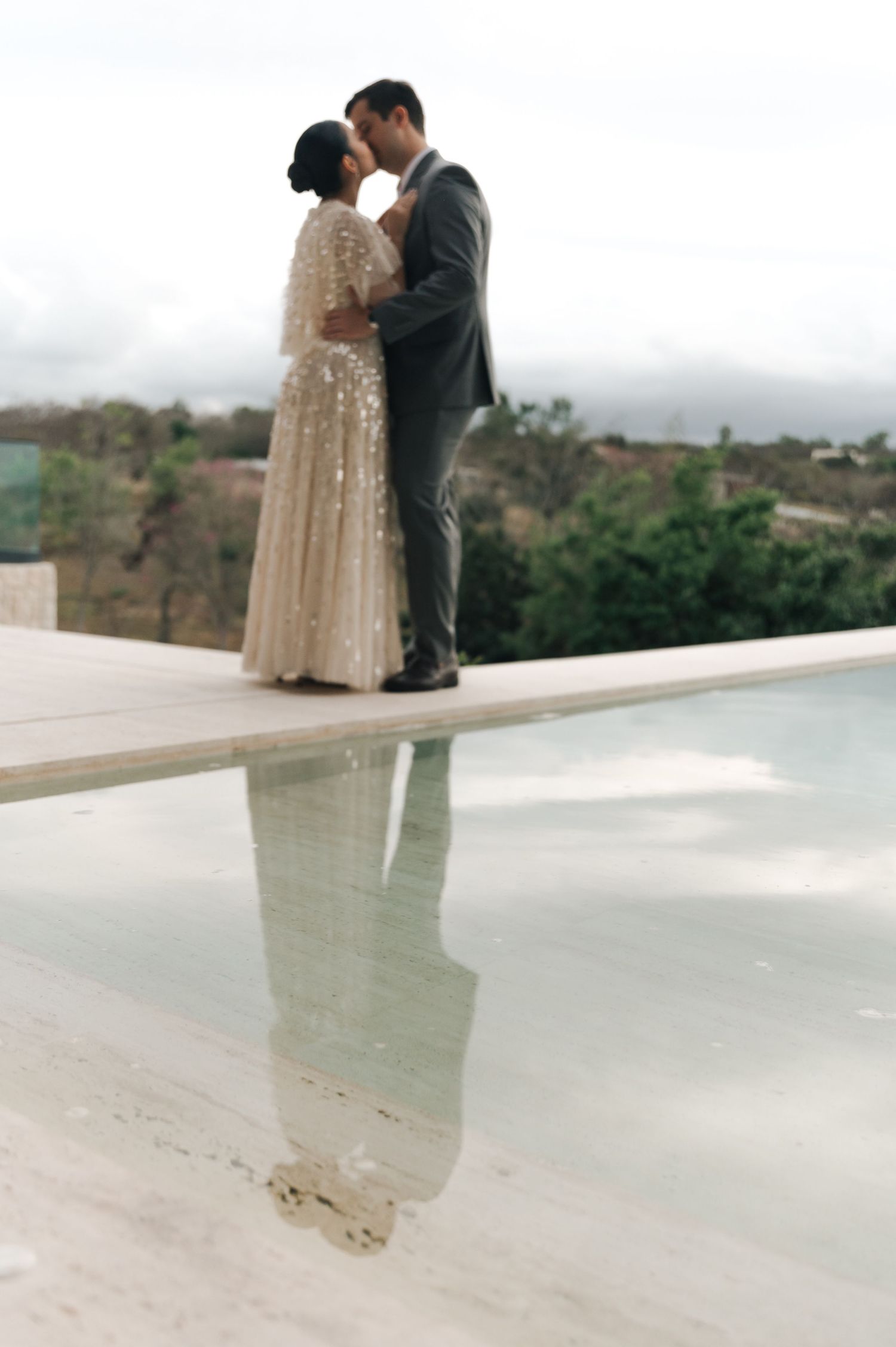 Romantic couple embracing near tropical plants and pink flowers.