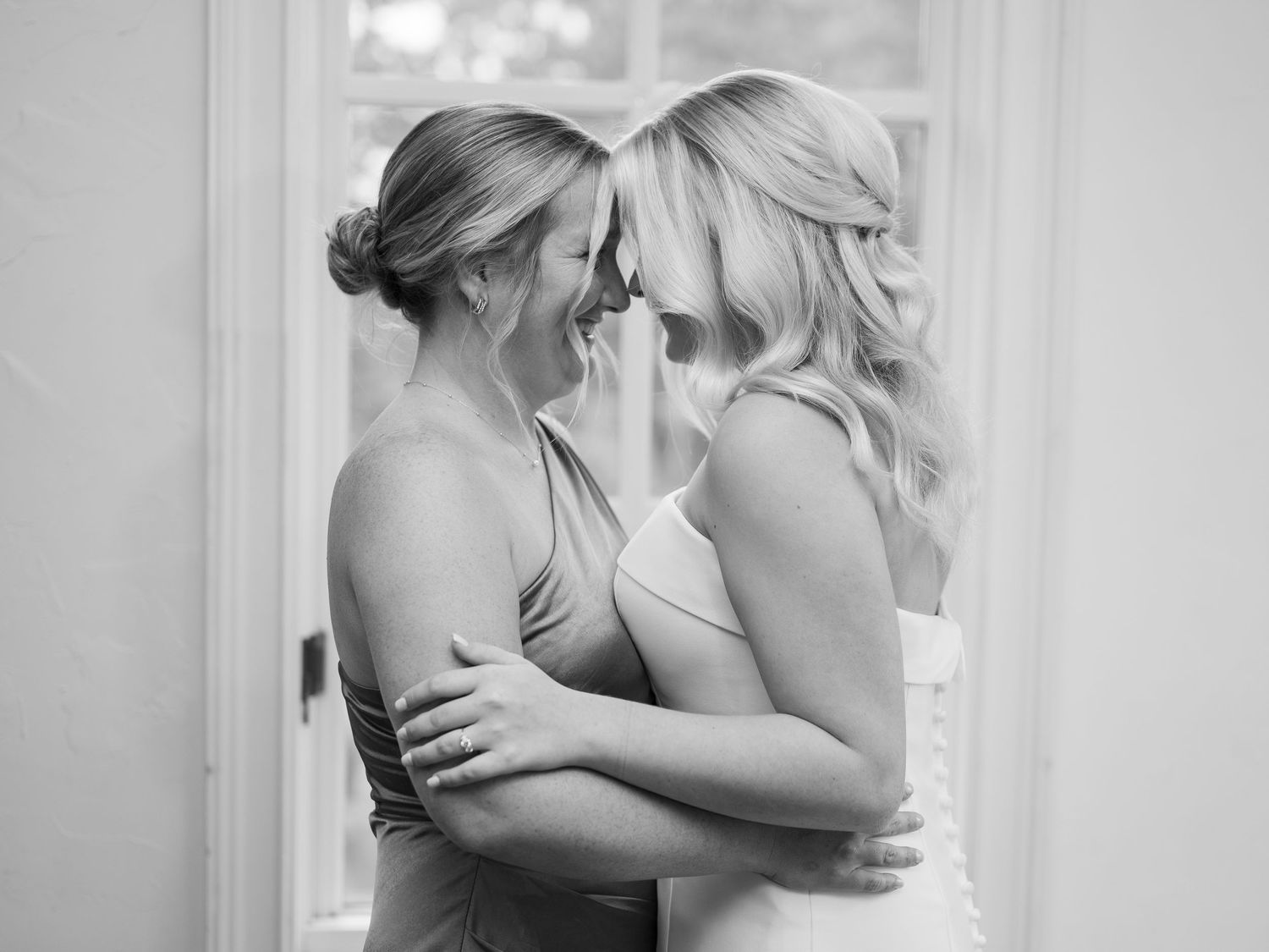 Intimate black and white wedding portrait of two people sharing a tender moment in soft light.