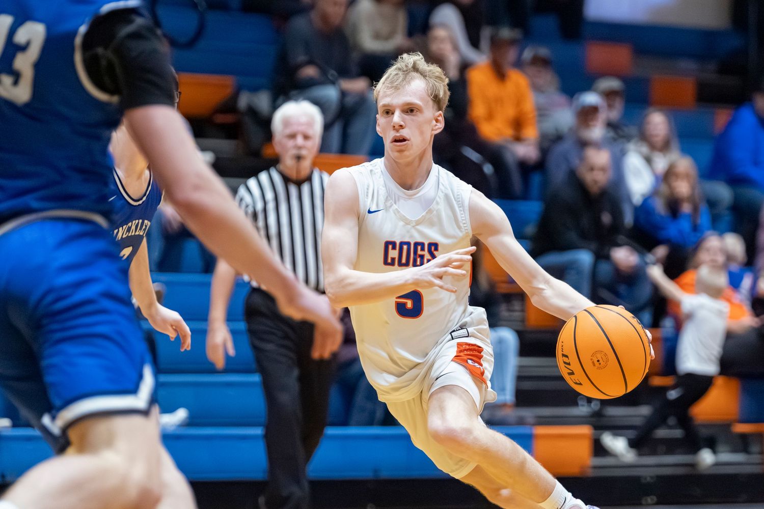 Basketball players compete for possession during fast-paced game action on indoor court.