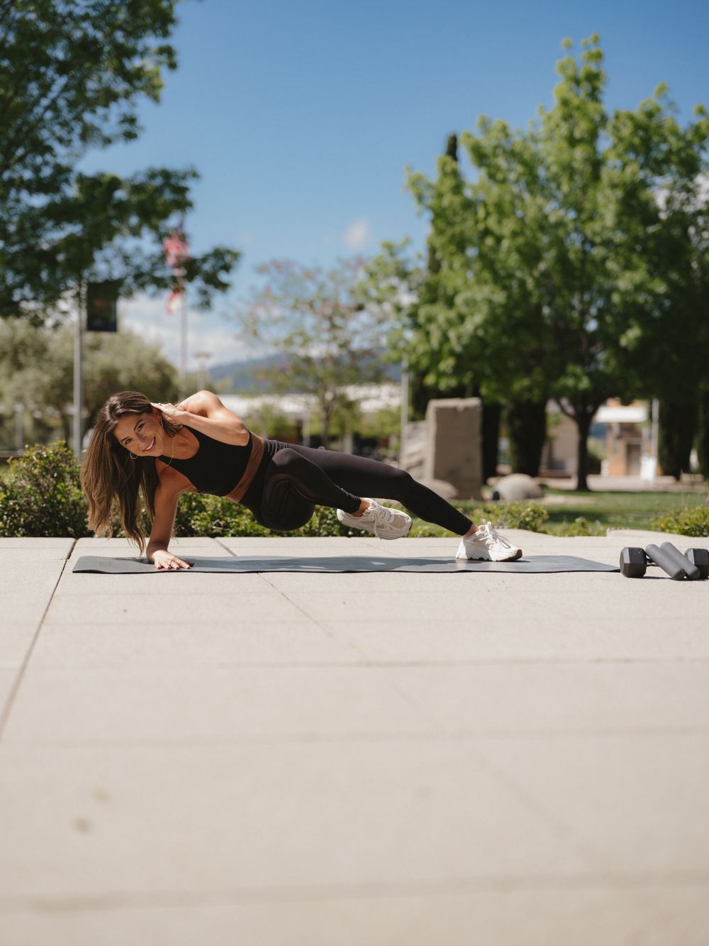 Outdoor fitness photo of someone doing a plank exercise on concrete with mountains in background.