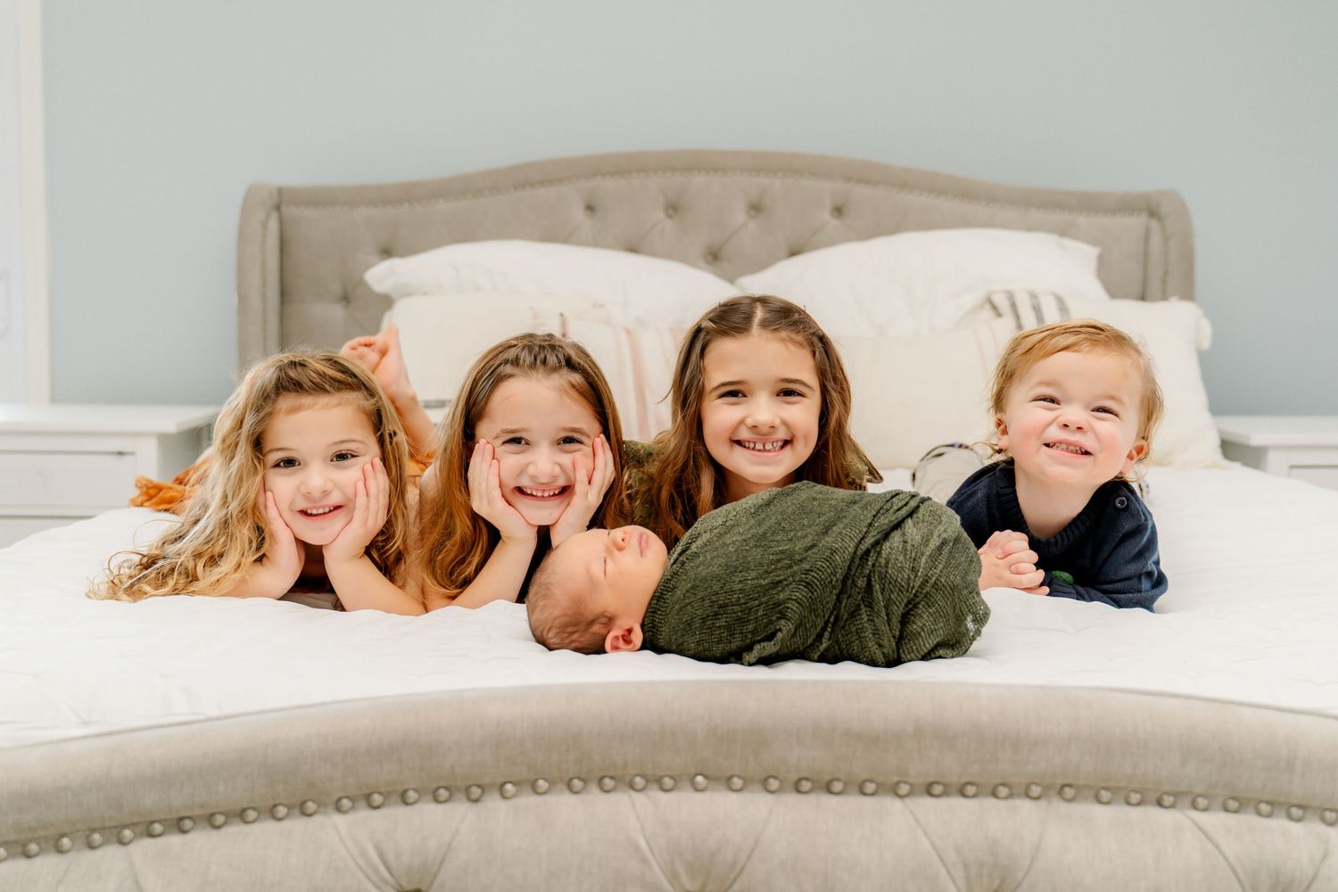 Happy children laying on bed together with joyful expressions.