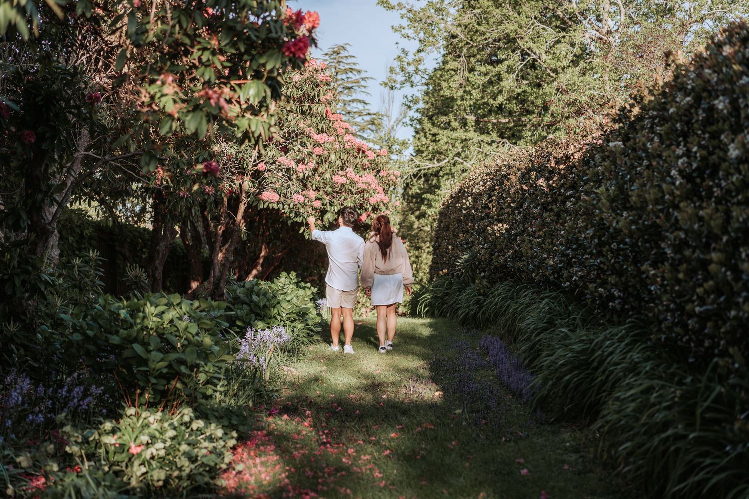 A romantic garden walkway with blooming flowers and greenery creates a serene path through lush landscaping.