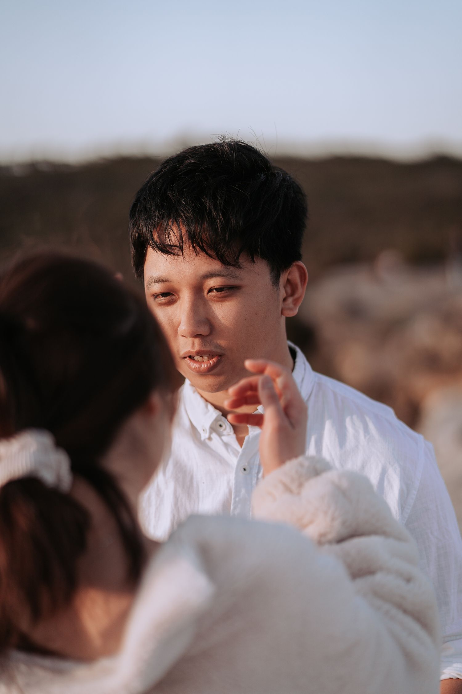 An intimate conversation between two people on a clifftop during golden hour.