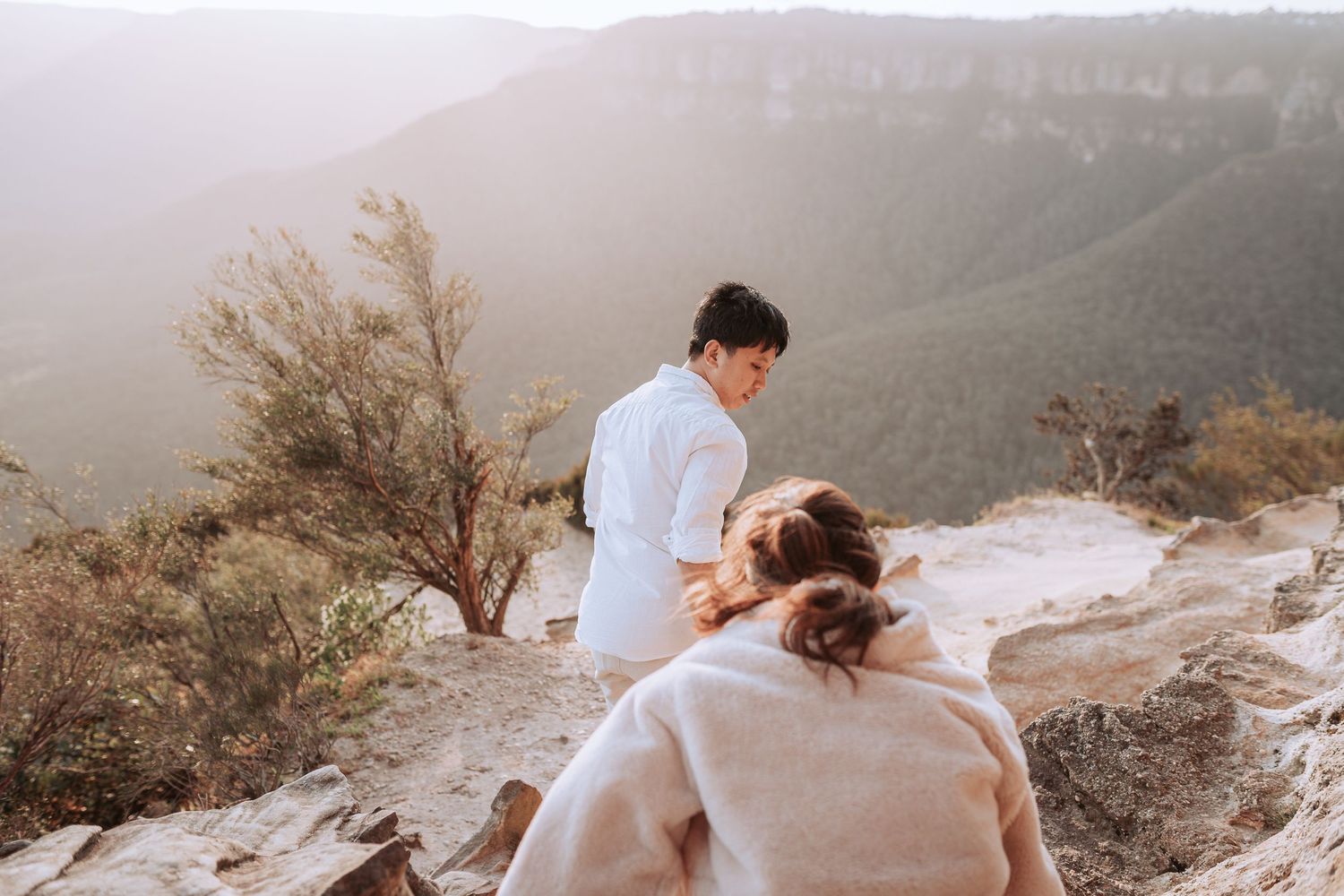 A couple sharing an intimate moment on a scenic mountain overlook during golden hour.