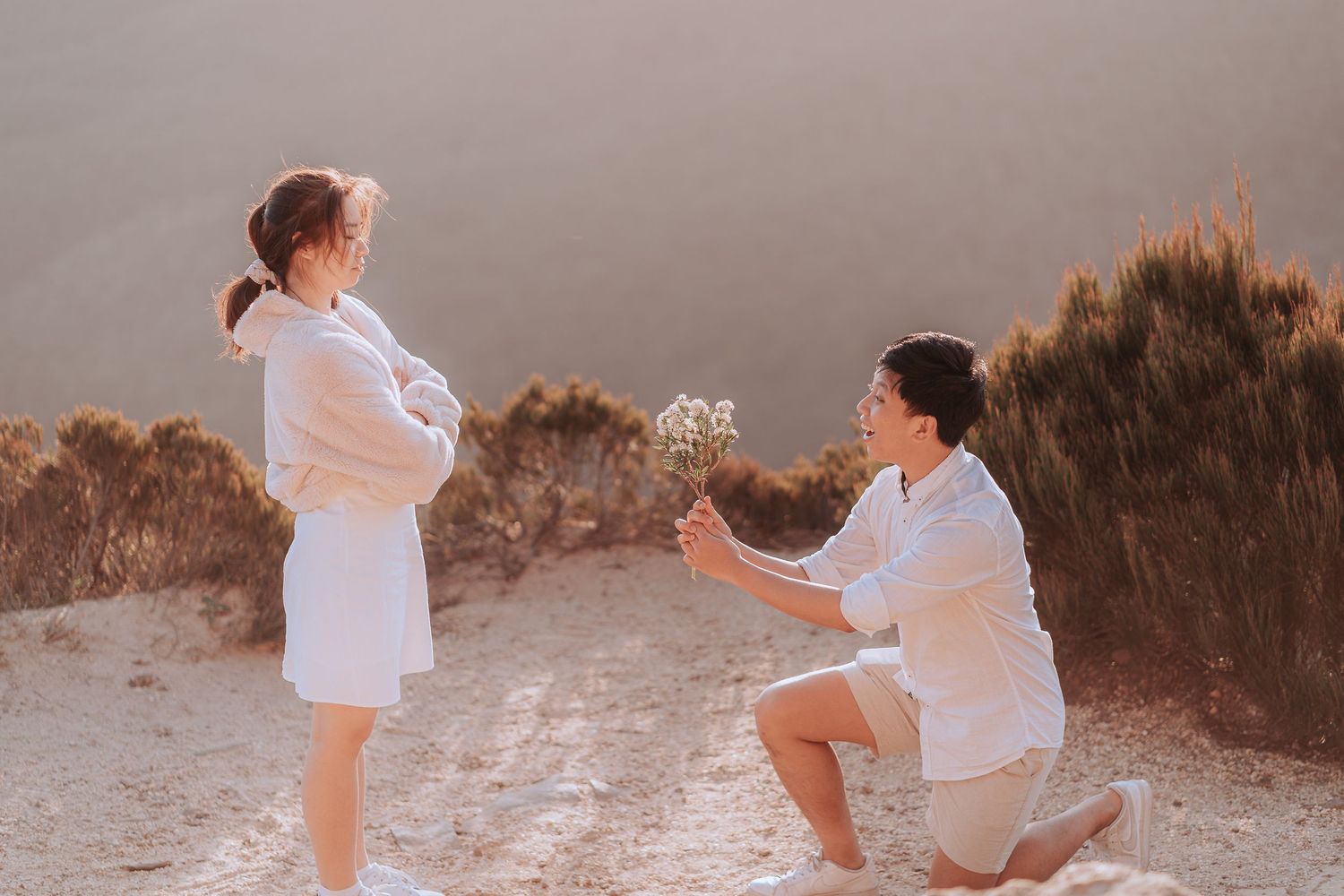 A marriage proposal taking place on a scenic mountain overlook at sunset.