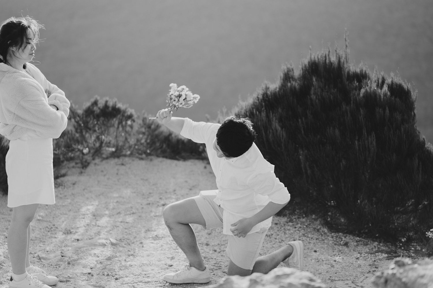 A black and white capture of a proposal moment on a mountain cliff.