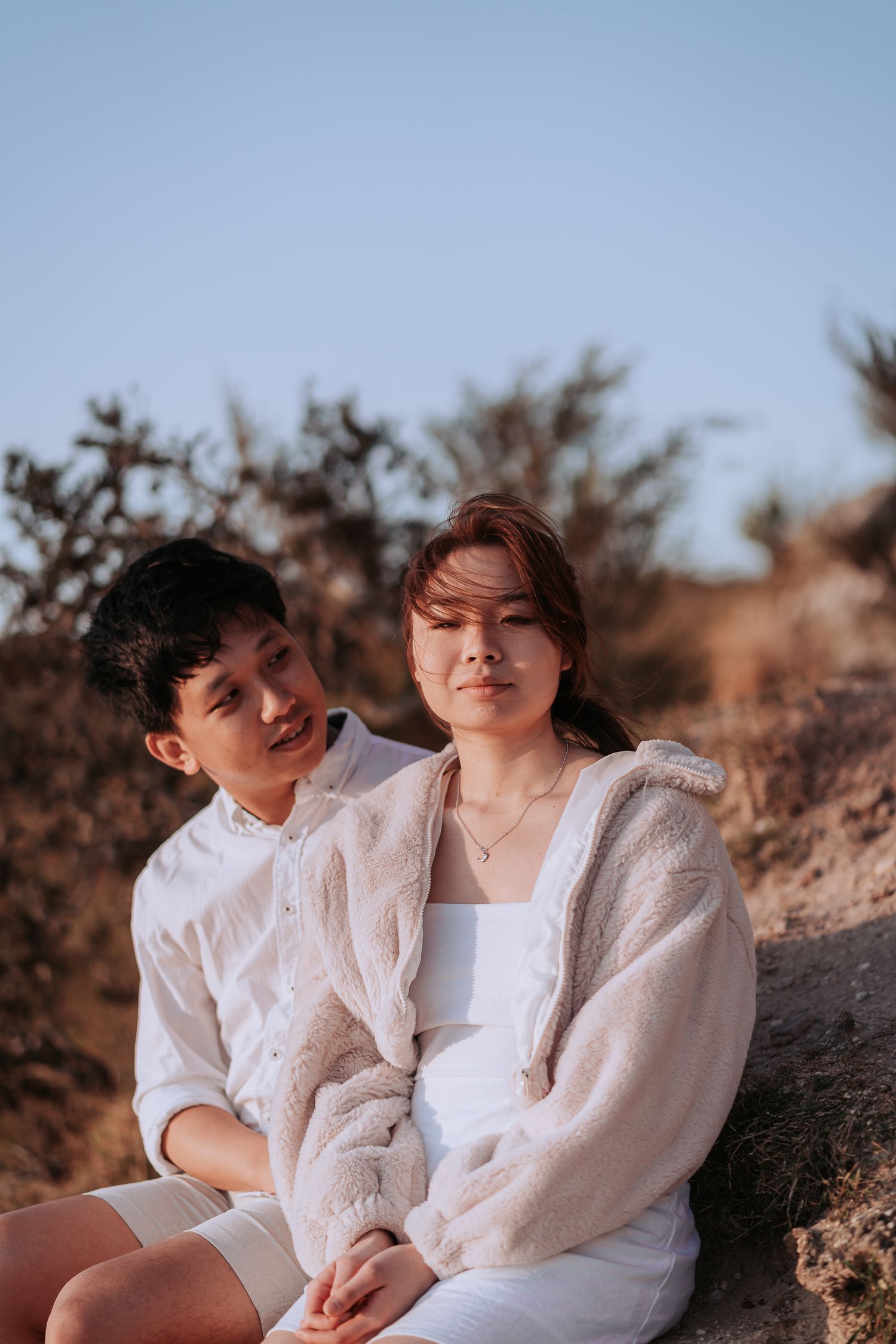 Intimate couple portrait against desert brush and blue sky.