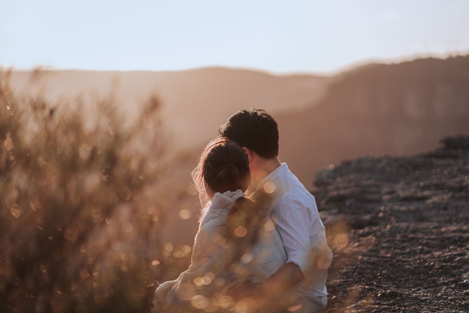 A couple shares a tender black and white moment against a misty mountain backdrop.