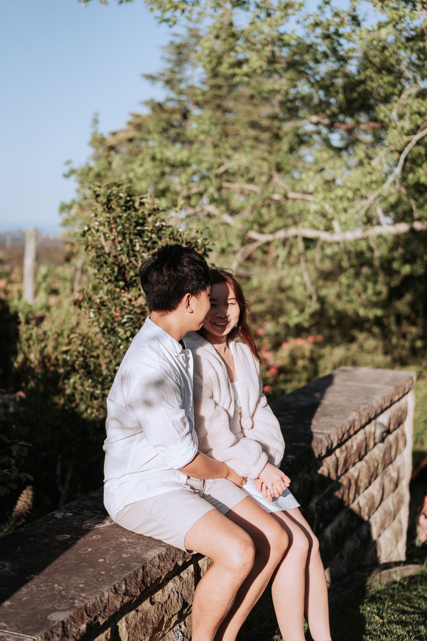 A couple in white outfits sharing an intimate moment while seated on stone steps.