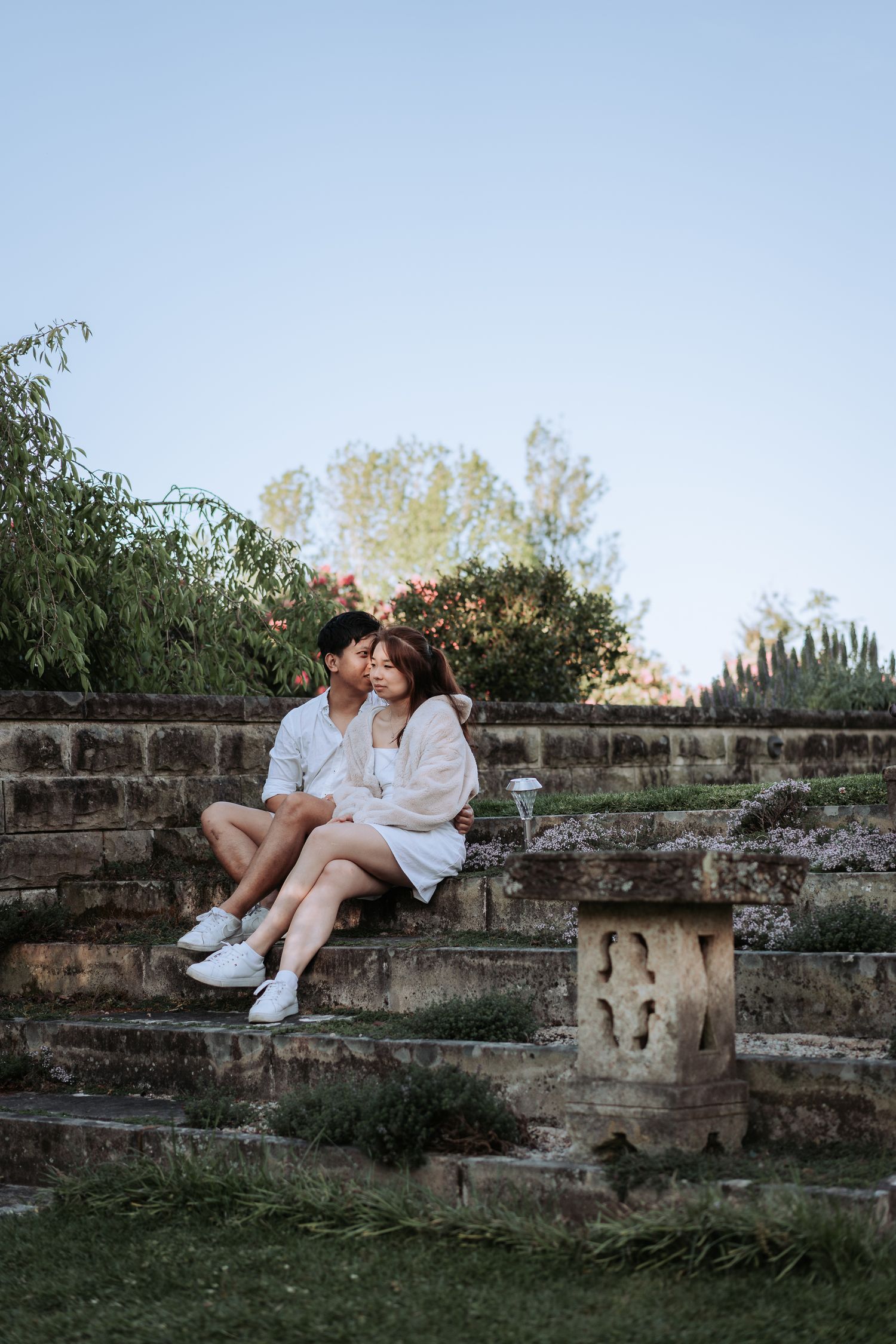 A tender moment shared between a couple sitting on ancient stone steps at sunset.