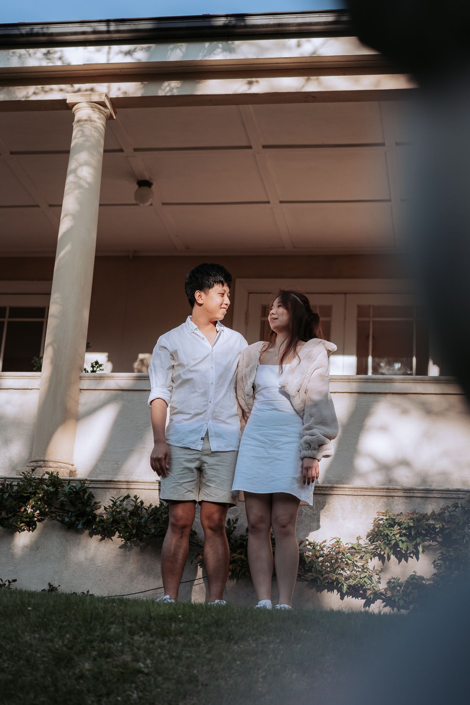 A couple shares a sweet moment together in front of a columned building.
