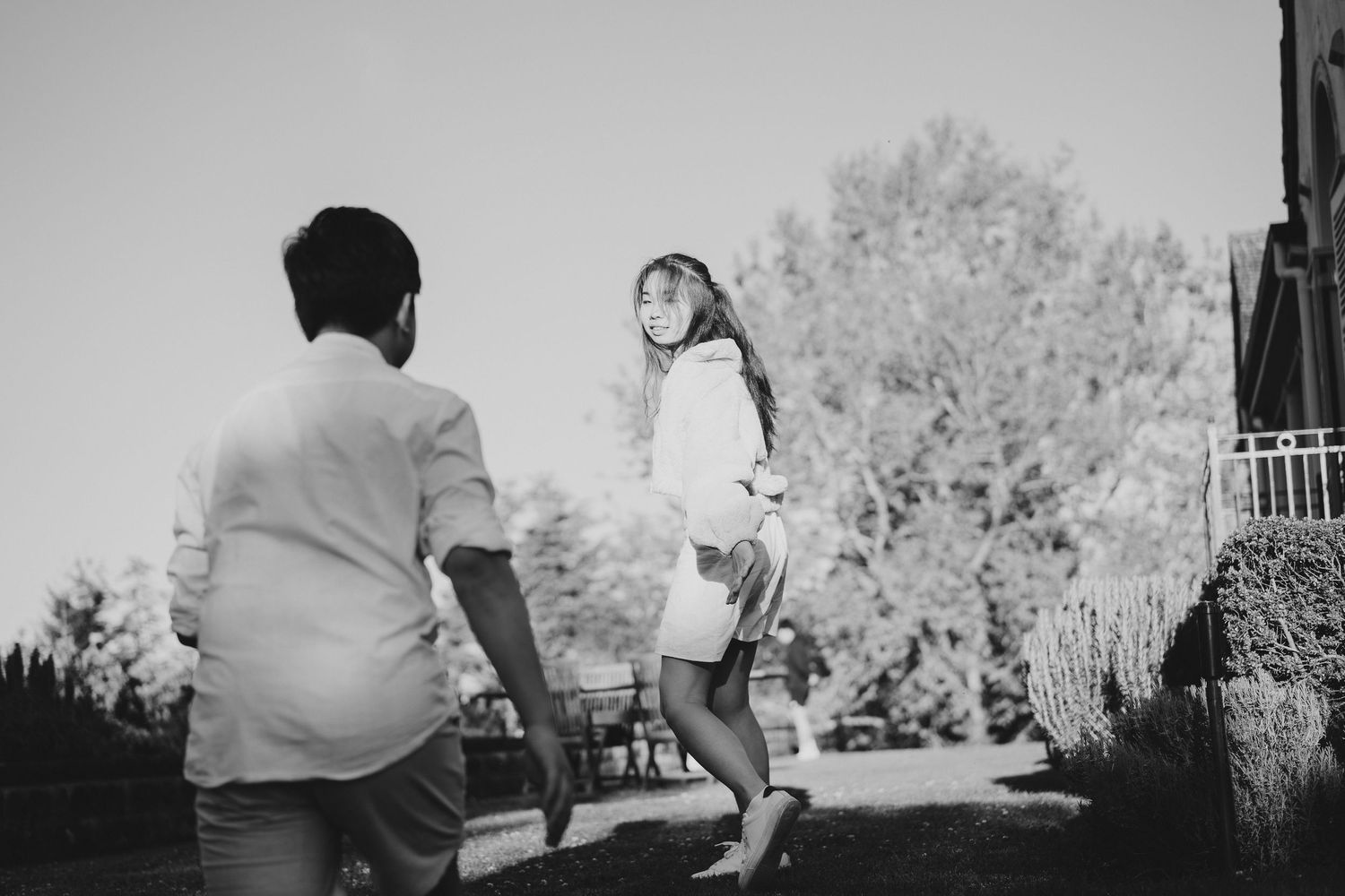 A candid black and white moment of two people interacting outdoors.