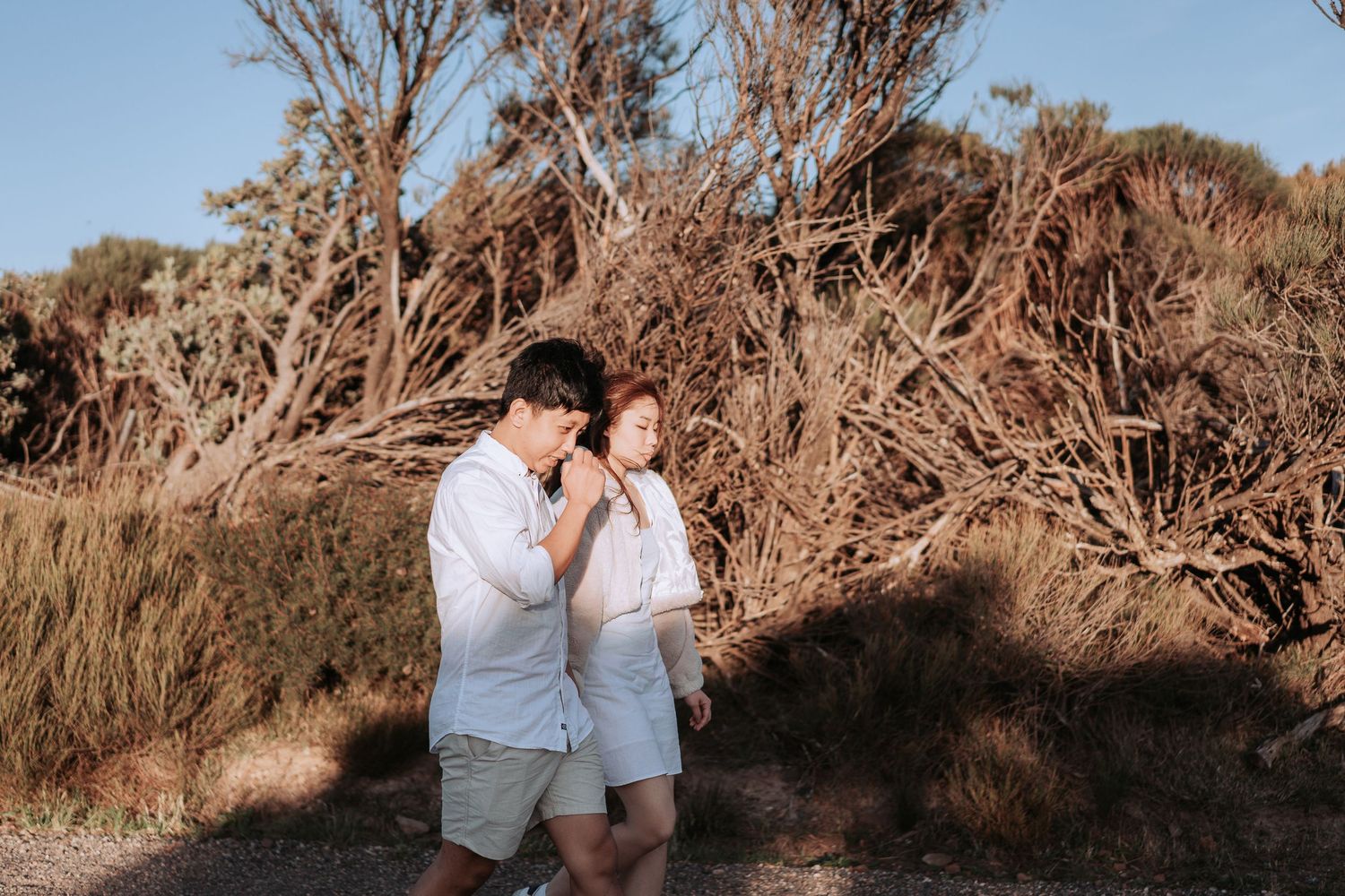 Couple sharing a playful moment on a nature trail surrounded by dry vegetation.