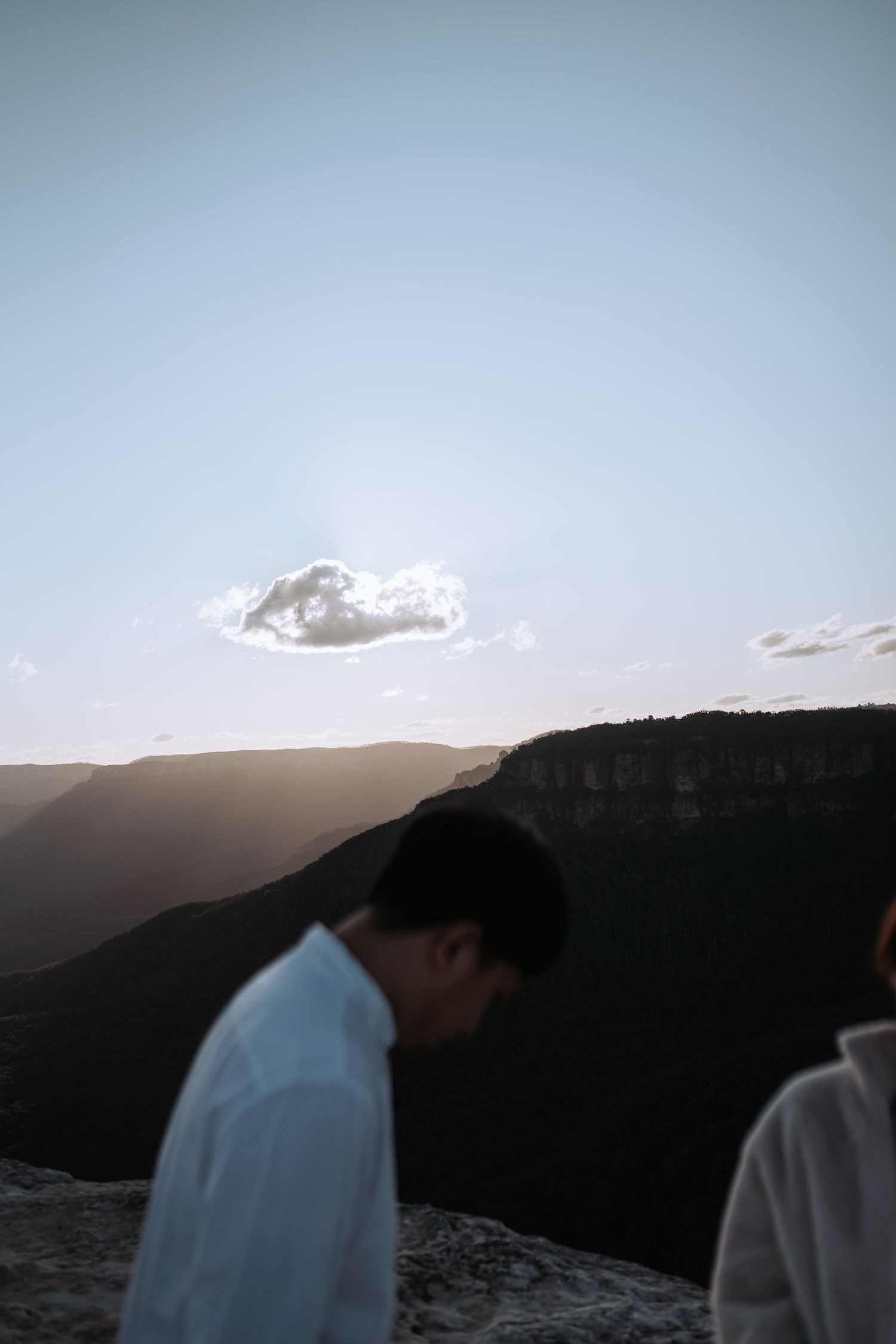 Silhouetted figure against mountain landscape during golden hour with dramatic cloud formations.