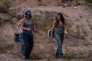 Two hikers with camping gear traverse a rugged desert trail in outdoor adventure gear.