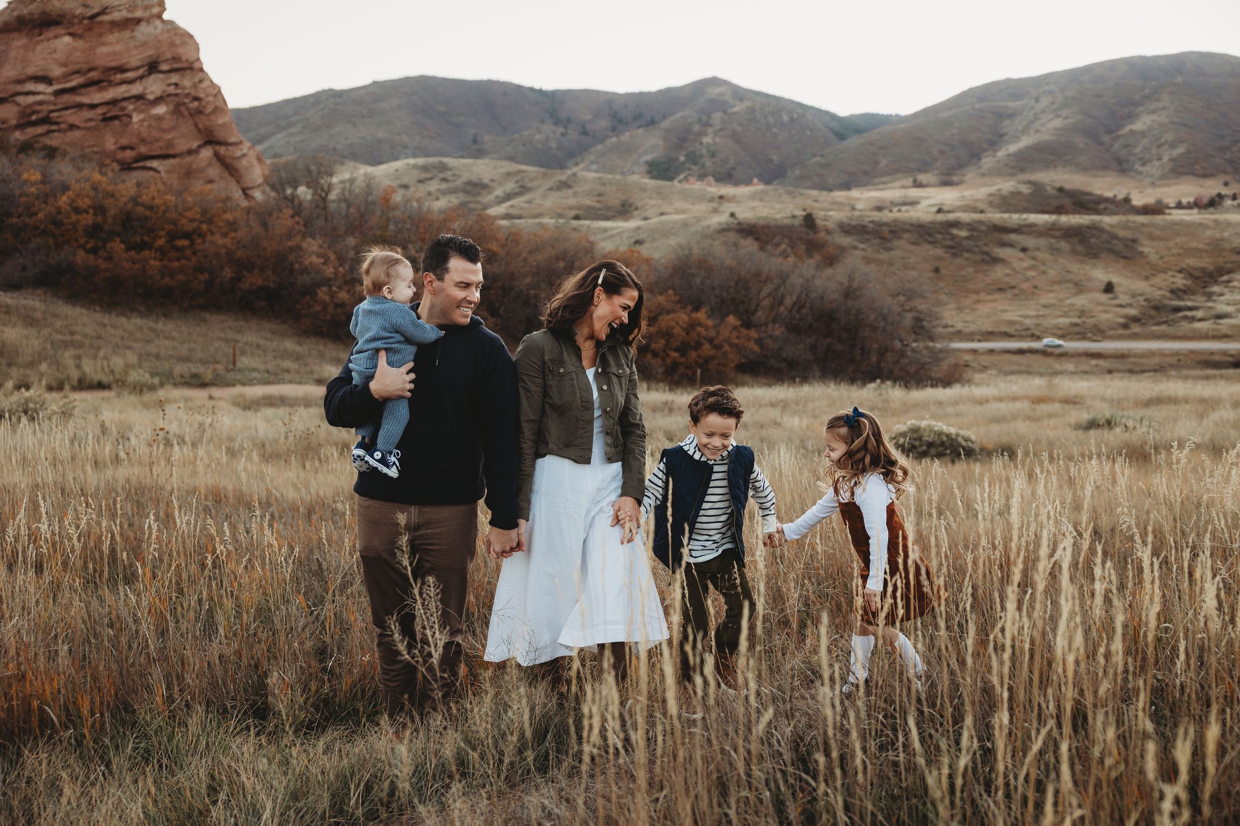 Denver family photography session with parents and children walking along a mountain trail during golden hour.