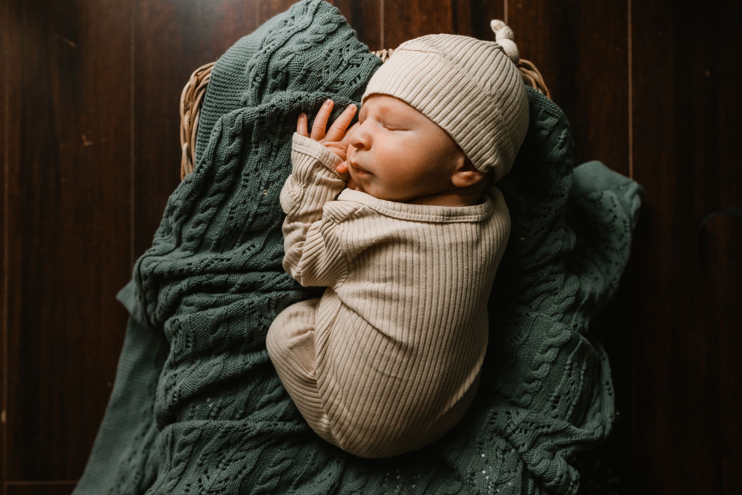 Candid newborn photography of a sleeping baby wrapped in a cream blanket during a Denver home session.