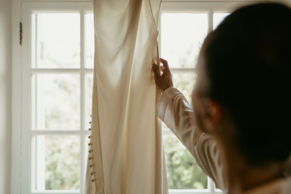 Sunlit white curtains being adjusted near bright windows in a getting ready room.