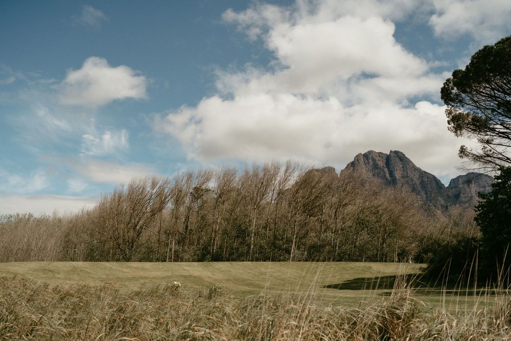 Mountain landscape with rolling fields and dramatic clouds in afternoon light.