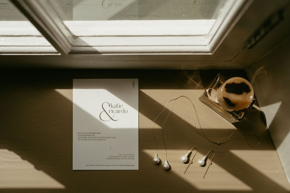 Wedding invitation and coffee cup casting shadows in dramatic natural lighting.