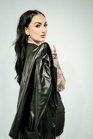 Edgy fashion portraits featuring black leather jacket and tattooed arms against light background.