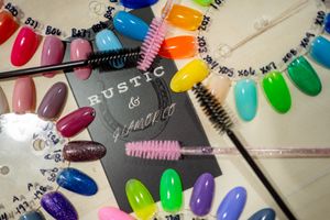 Colorful nail polish swatches displayed with brushes and beauty supplies.