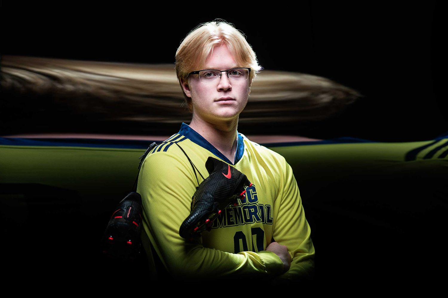 Athletic player in yellow jersey poses dramatically against dark background.