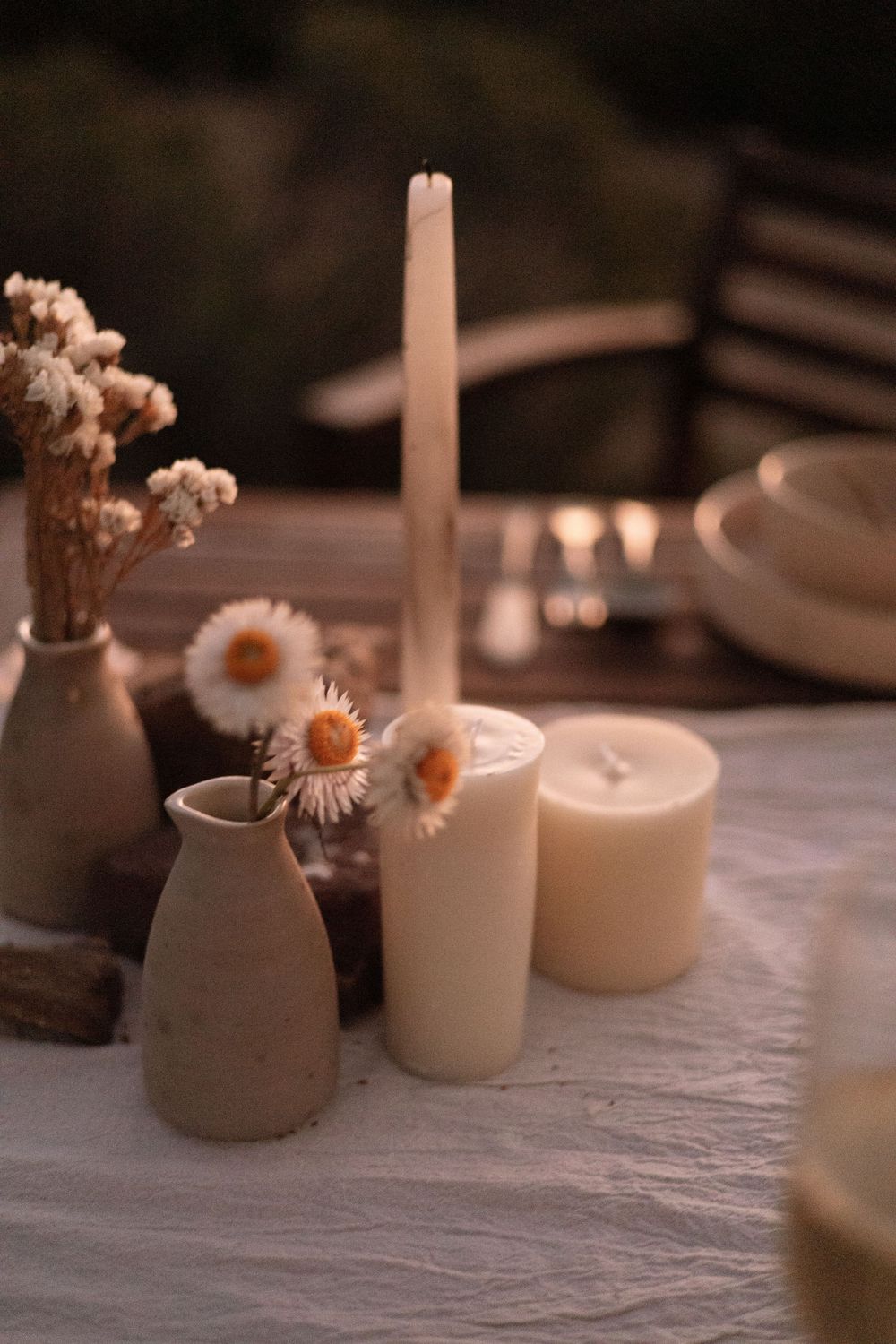 Minimalist tablescape with white candles and dried flowers in muted tones.
