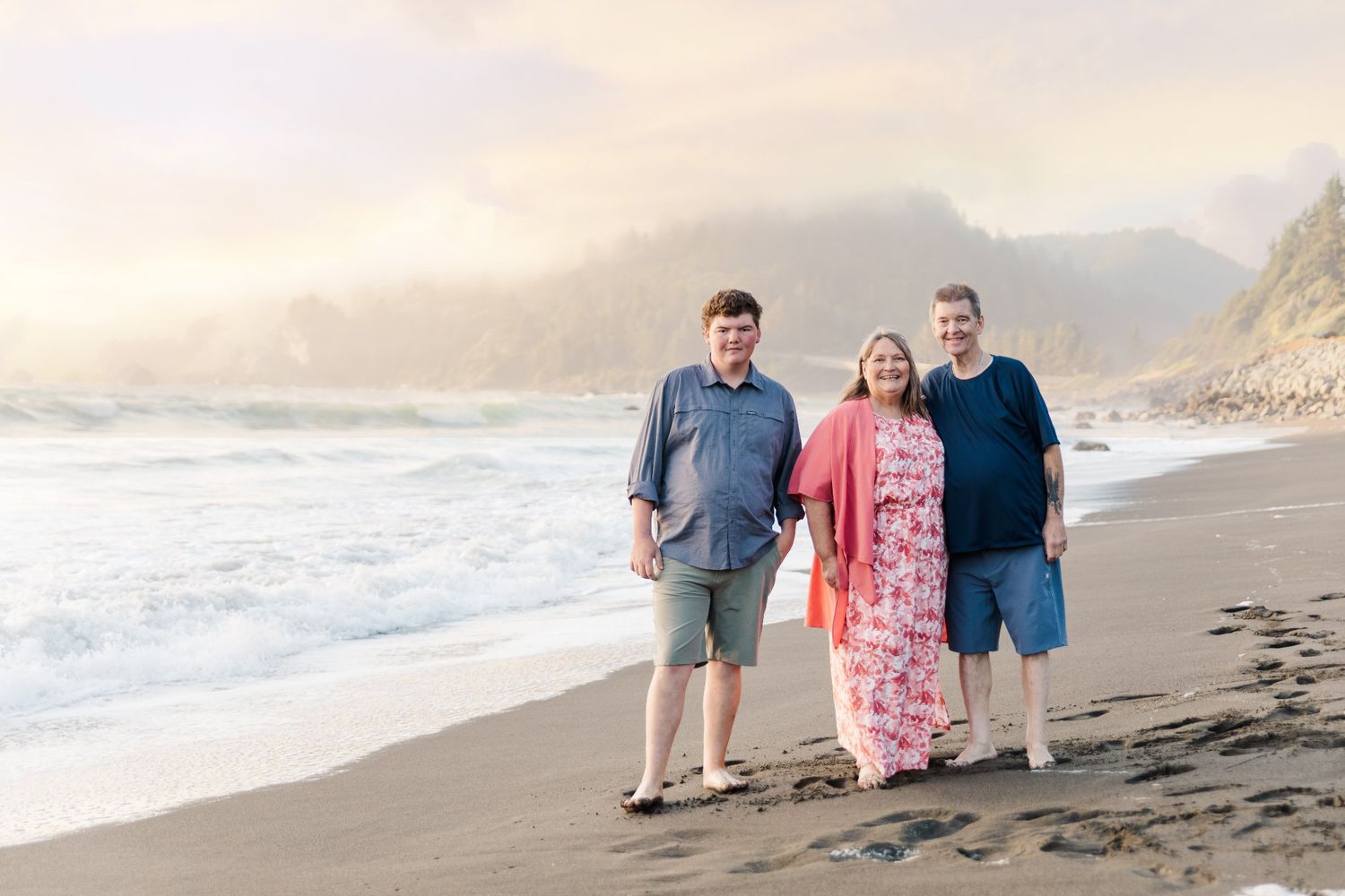 Small groups pose for casual photos along a scenic beach at golden hour.