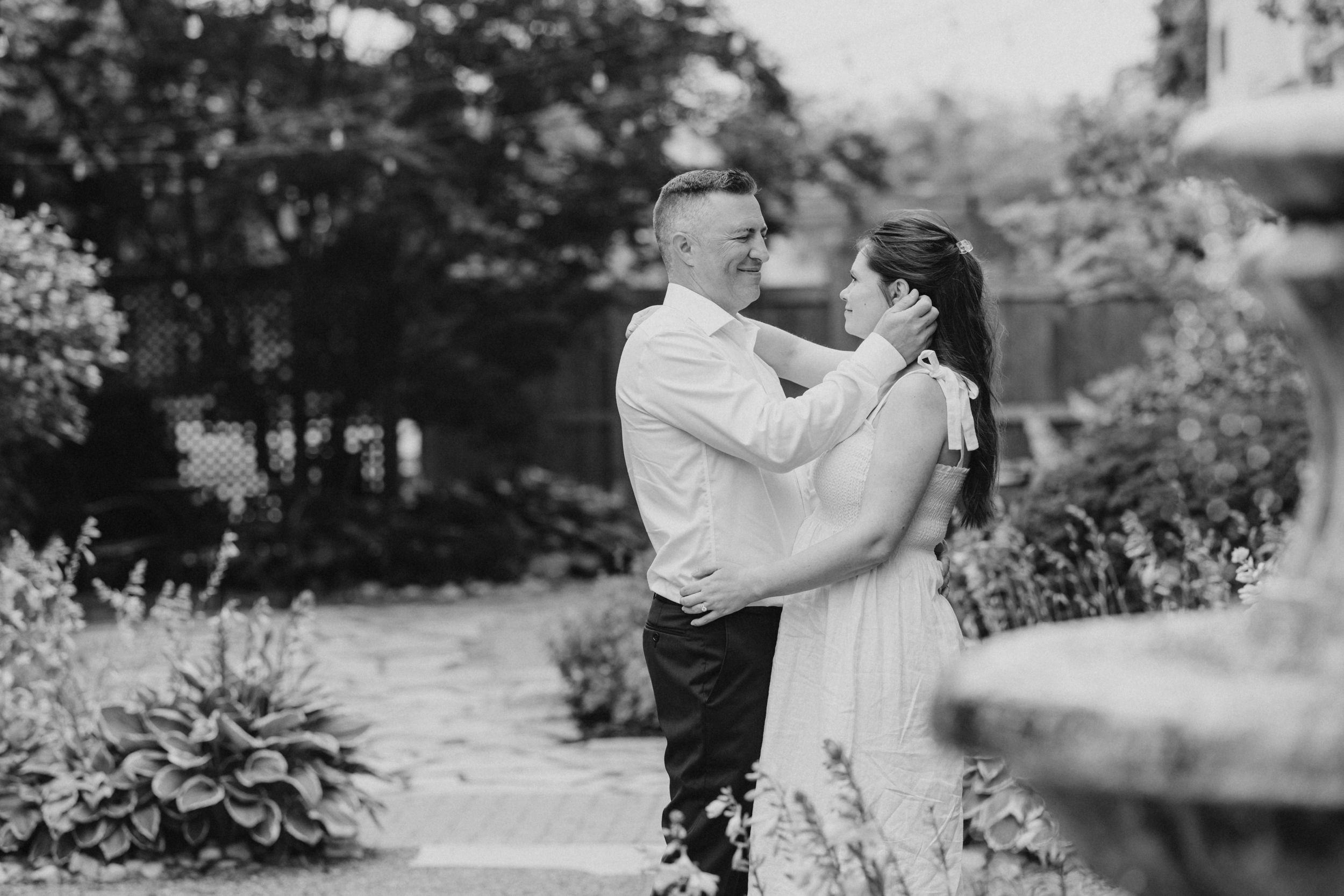 A series of romantic black and white photos showing a couple sharing tender moments in an outdoor garden setting.