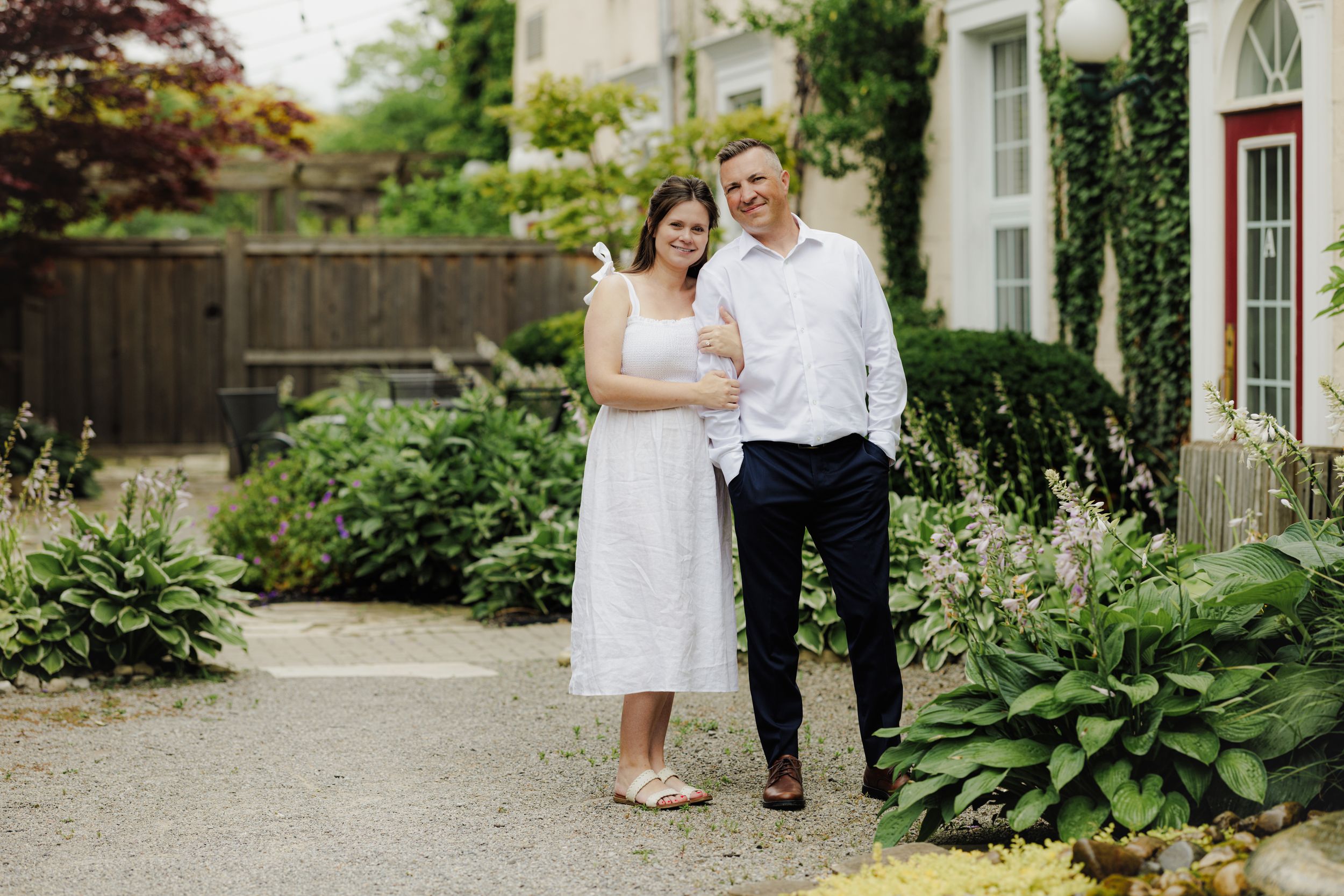 A romantic garden portrait featuring a white dress and formal attire amidst lush greenery and garden paths.