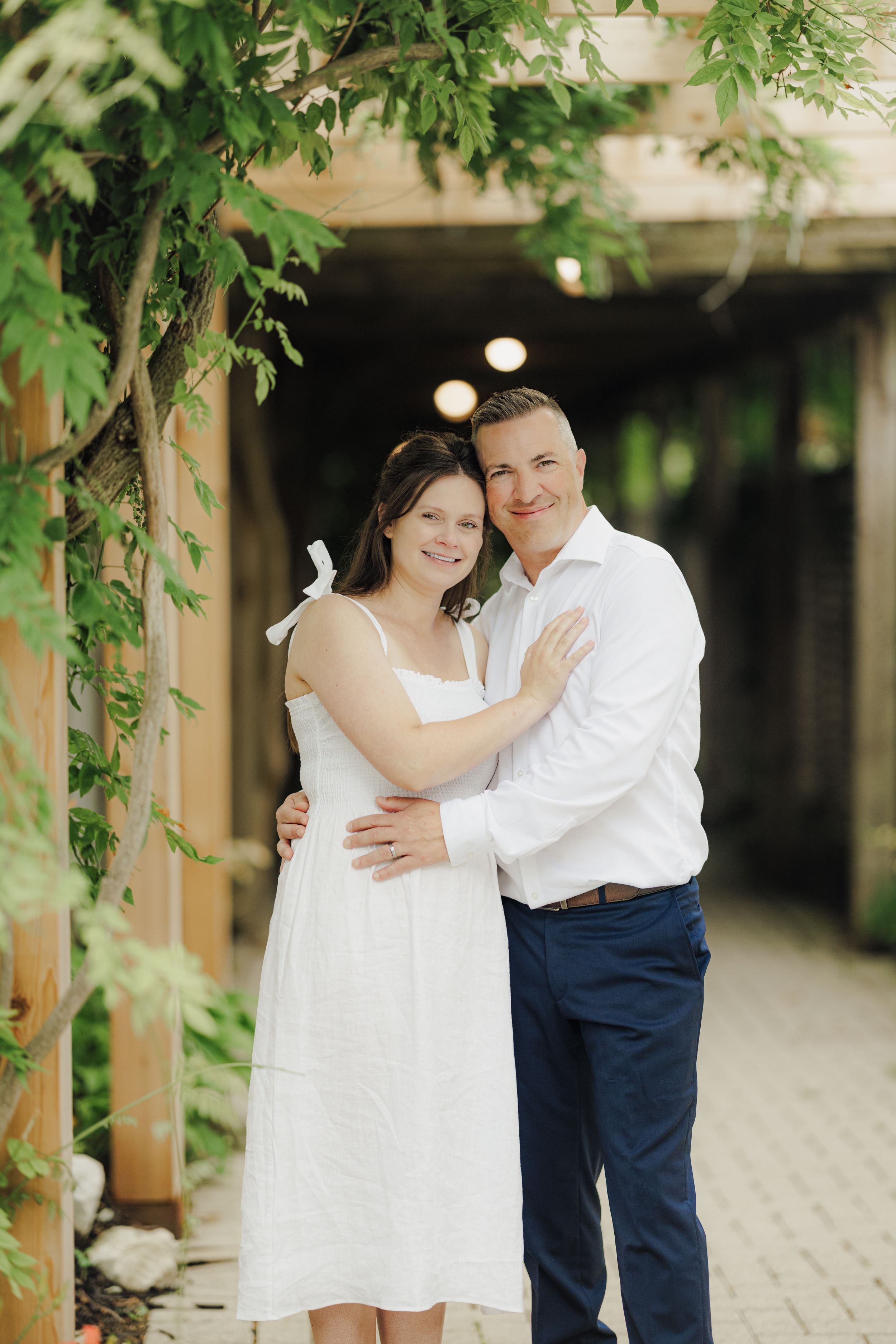 A romantic outdoor photo sequence shows a couple embracing under lush greenery in a courtyard setting.