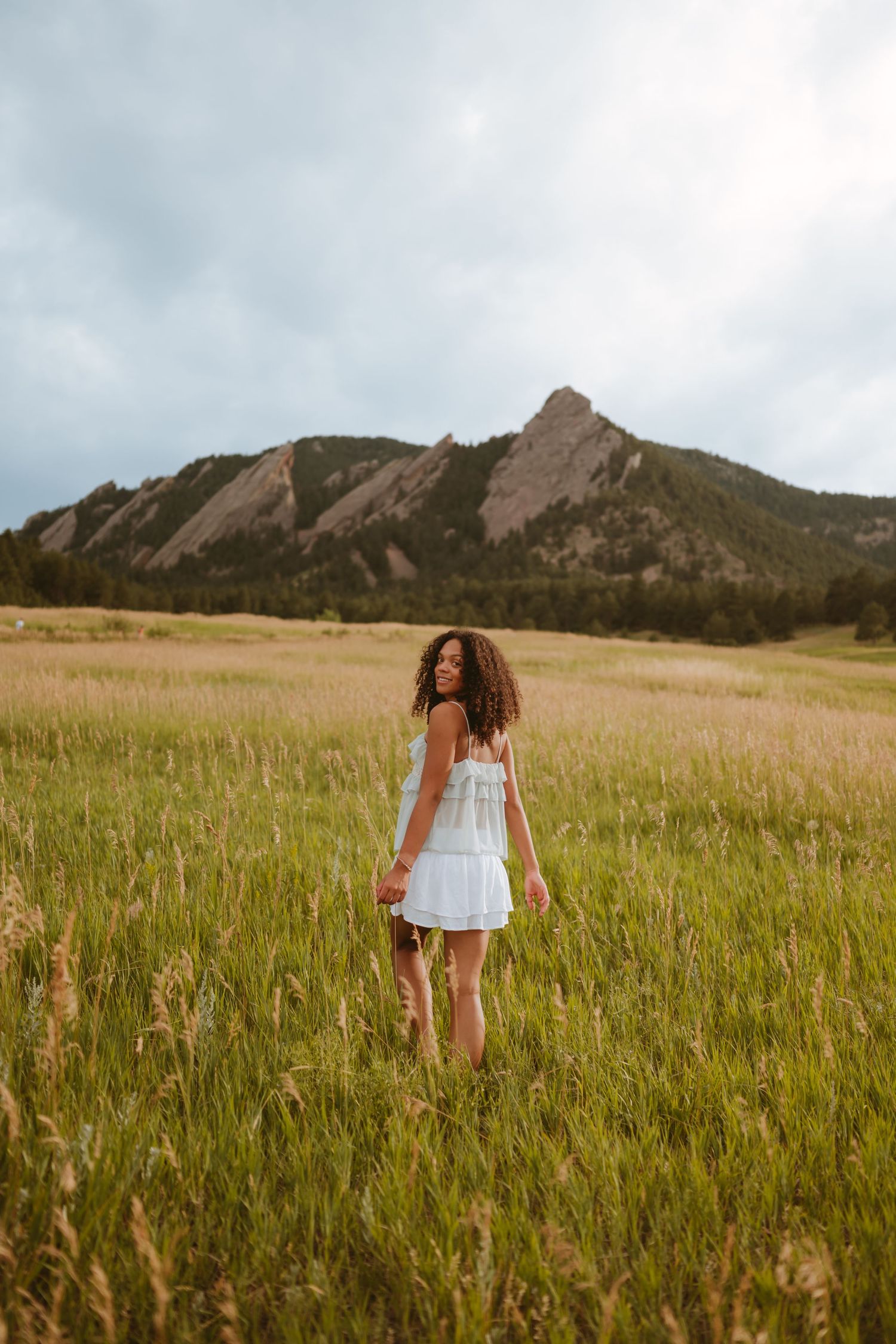 A series of images showing a person exploring a grassy meadow with dramatic Flatiron mountains in Boulder, Colorado.