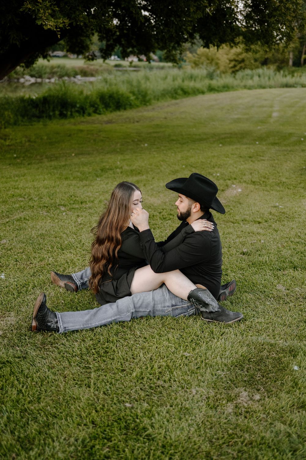 A couple lying on grass together during a romantic outdoor photo session.