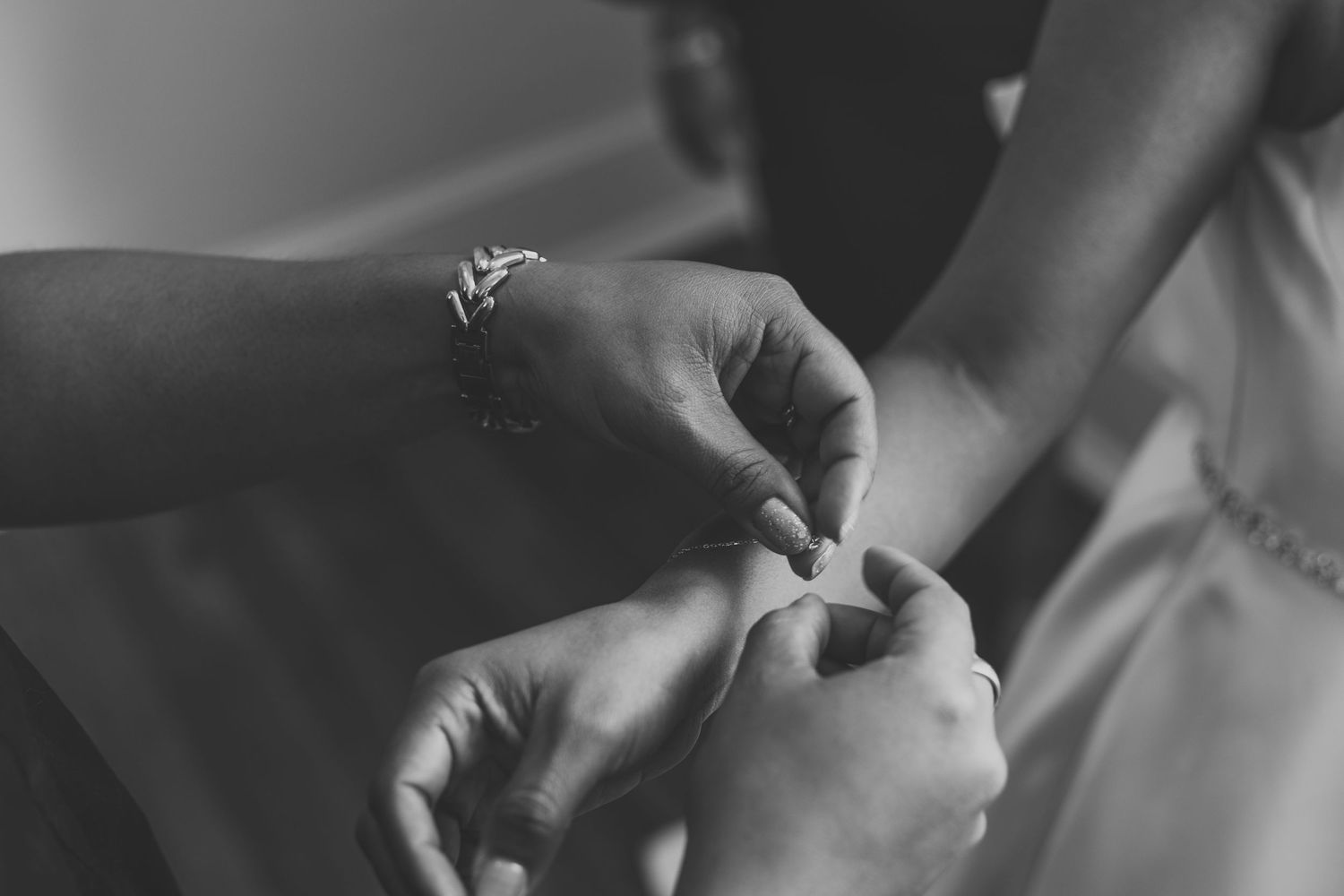 Black and white detail shot of hands during a wedding preparation.