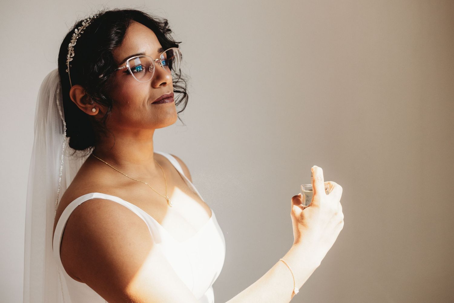 Wedding preparation scene in natural light against a neutral wall.