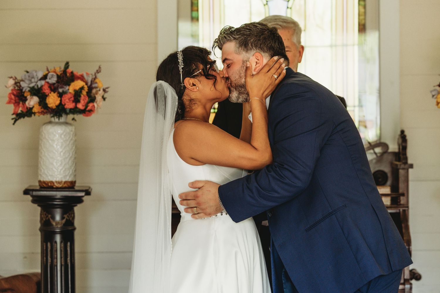 A couple shares a romantic moment in an elegant indoor setting with floral decorations.